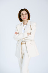 Portrait of a confident business woman in a beige pantsuit and a white blouse on a white...