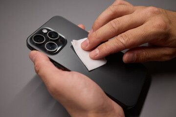 A person is wiping a cell phone clean with a tissue