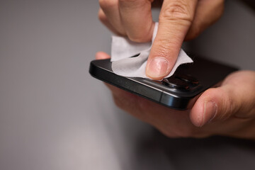 A person is wiping a cell phone clean with a tissue