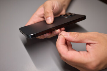 A person is inserting a sim card into a cell phone using hand and fingers