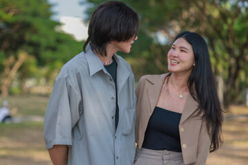 Obraz premium Asian couples playfully bond, sharing affectionate gazes, laughter, and intimate warmth outdoors.