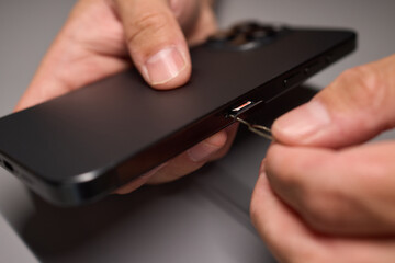 A person is inserting a sim card into a cell phone using hand and fingers