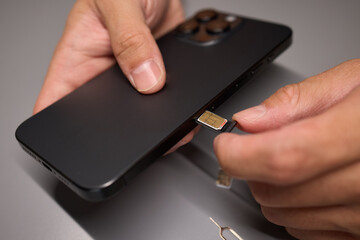 A person is inserting a sim card into a cell phone using hand and fingers