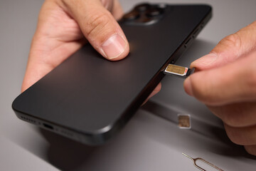 A person is inserting a sim card into a cell phone using hand and fingers