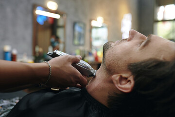 Cropped image of barber shaving neckline of client