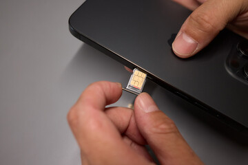 A person is inserting a sim card into a cell phone using hand and fingers