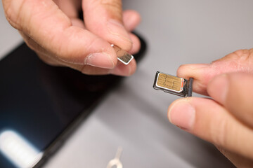 A person is inserting a sim card into a cell phone using hand and fingers