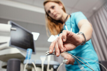 A cardiologist is doing a procedure to check the heart. Cardiologist put electrocardiogram equipment on patient chest and do cardiogram test.