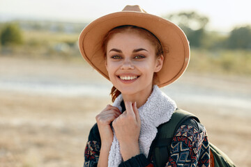 Happy young woman in stylish hat and scarf enjoying a peaceful day in the countryside