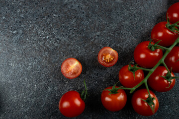 Top view of fresh red ripe tomatoes on dark concrete background. Tomato halfs on table. Copy space