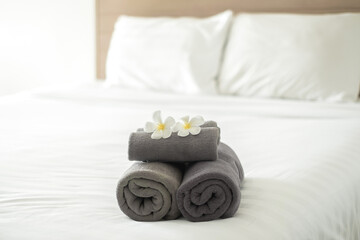 A hotel maid stacked towels on the bed and placed flowers on the towels in a hotel room