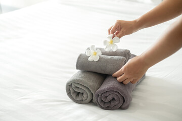 A hotel maid stacked towels on the bed and placed flowers on the towels in a hotel room