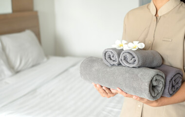 A hotel maid stacked towels on the bed and placed flowers on the towels in a hotel room