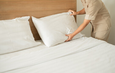 The hotel maid cleans and makes the bed in the hotel room