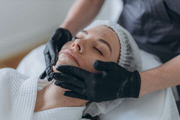 portrait of a young attractive woman getting facial massage with cream. 