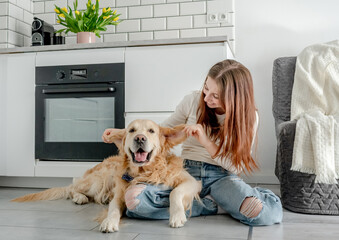 Teenage Girl With Golden Retriever Dog At Home In Kitchen