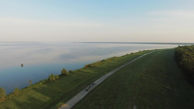 Aerial Scenic View Of Pick-Up Truck Pulling Boat By Tranquil River, Drone Flying Upwards Over Green Landscape - Bayou Vista, Texas