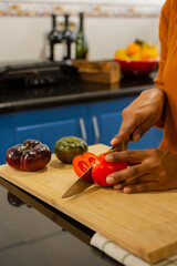Close-up of a woman's hands cutting tomatoes on a cutting board in the kitchen at home