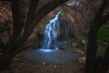 Beautiful Karaungir waterfall between trees next to the cave of an ancient man in the Turkestan region of Kazakhstan