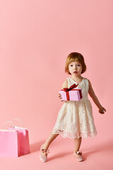 Little girl in white dress holding pink gift box.