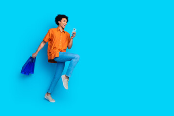 Full length photo of funky cool guy dressed orange shirt holding bargains shopping modern device...