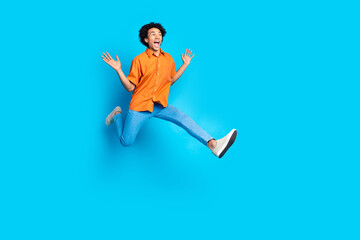 Full length photo of cheerful positive guy dressed orange shirt jumping high empty space isolated...