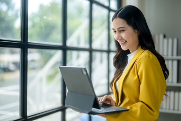 A woman is sitting in front of a window with a laptop in her lap