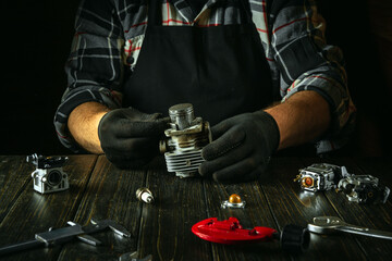 A foreman at a workbench in a workshop repairs the engine of a lawn mower after a breakdown....