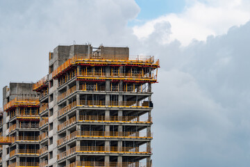 Top part of a skyscraper under construction with the cloudy sky