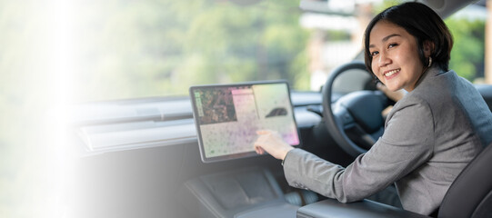 A woman is sitting in a car and using a tablet to navigate