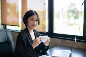 A woman in a black suit holding a white coffee cup