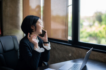 Fototapeta premium A woman is talking on her cell phone while sitting at a desk