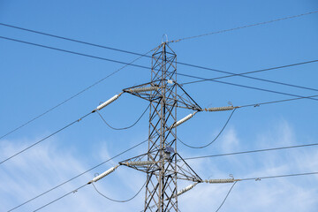 An electric pylon on a beautiful sunny summers day with white fluffy clouds in the sky.