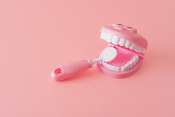 a dental model toy with dental tool on pink background for infant dental care and hygiene