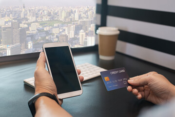 Person making an online payment using a smartphone and credit card, representing mobile banking and digital transactions.