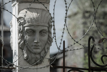 A bas-relief depicting a human face with a sad expression, surrounded by barbed wire