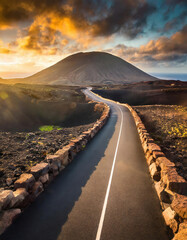 A paved road winding through picturesque scenery leading to the destination with a towering mountain backdrop.