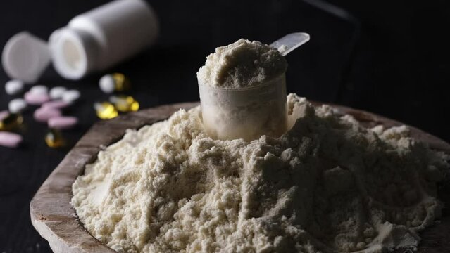 Rotating scoop with whey dry powder protein enhances sport, food, healthy life concept.
