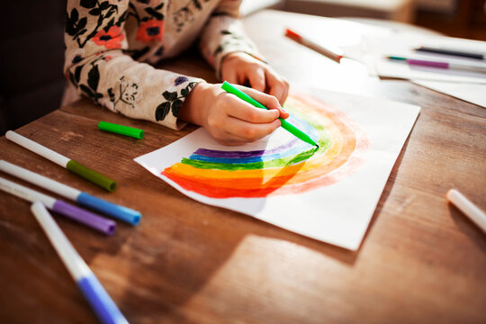 Little girl drawing a rainbow at home