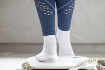 A woman stands on the scale. Legs of a person on a scale