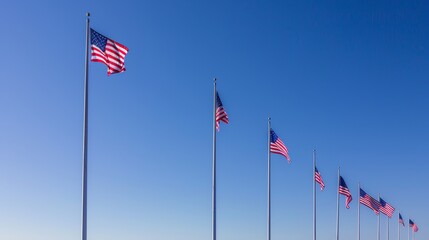 Obraz premium Memorial Day tribute with rows of American flags waving at half-staff, symbolizing respect and remembrance for fallen heroes. Clear blue sky and a peaceful atmosphere. Copy space for text
