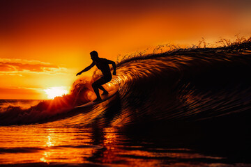 Silhouette of a surfer riding waves at sunset