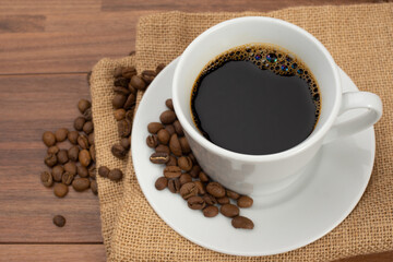 木目テーブルの上に置かれたコーヒーカップとコーヒー豆