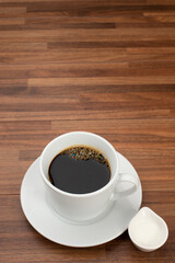 木目テーブルの上に置かれたコーヒーカップとコーヒーフレッシュ