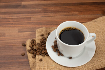 木目テーブルの上に置かれたコーヒーカップとコーヒー豆