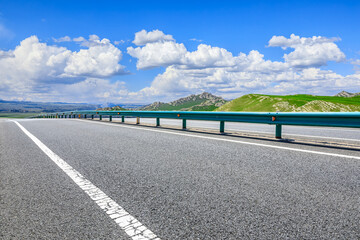 Asphalt highway road and mountains with beautiful sky clouds on a sunny day