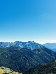 Obraz premium A panoramic view of a mountain range with a clear blue sky, perfect for themes of adventure and natural beauty