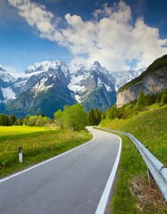 Fototapeta premium transport road in the Alps against the backdrop of snow-capped mountains and forest