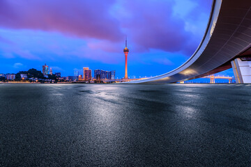 Asphalt road and bridge with modern city buildings at night in Macau