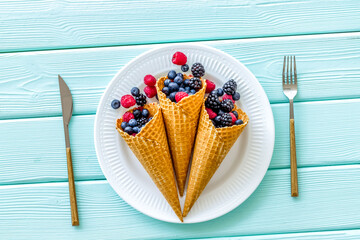 breakfast with fresh berries in waffle cones and tableware on se